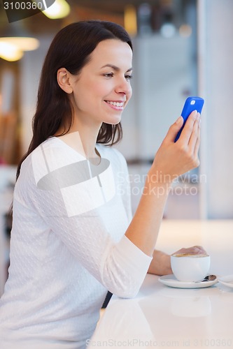 Image of smiling woman with smartphone and coffee at cafe