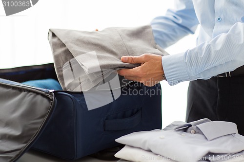 Image of businessman packing clothes into travel bag