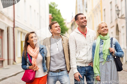 Image of group of smiling friends walking in the city