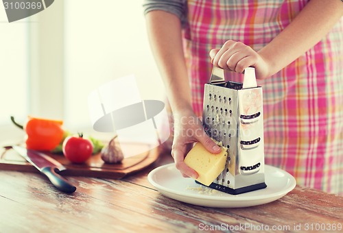 Image of close up of female hands grating cheese