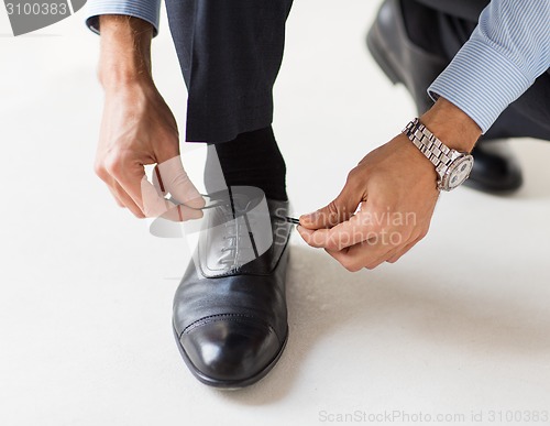 Image of close up of man leg and hands tying shoe laces
