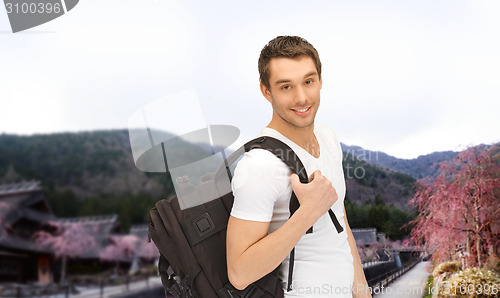 Image of happy young man with backpack and book travelling