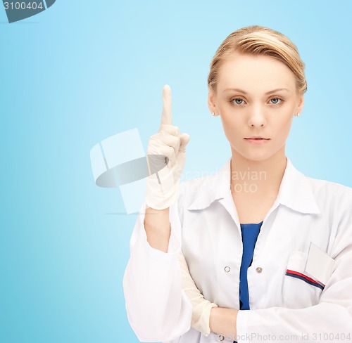 Image of smiling young female doctor pointing her finger up