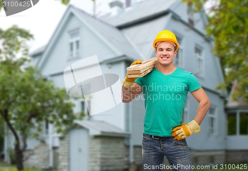 Image of smiling manual worker in helmet with wooden boards