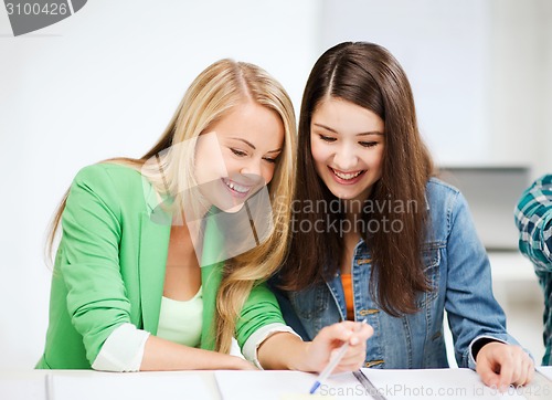 Image of student girls pointing at notebook at school