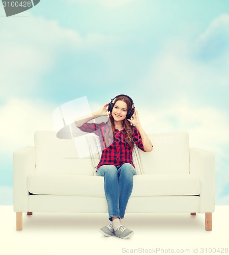 Image of teenage girl sitting on sofa with headphones