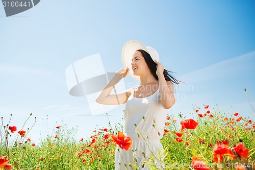 Image of smiling young woman in straw hat on poppy field