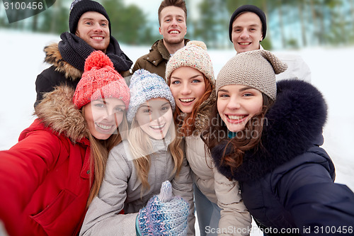 Image of group of smiling friends taking selfie outdoors