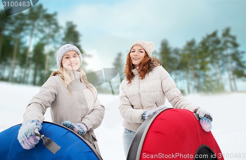 Image of happy girl friends with snow tubes outdoors