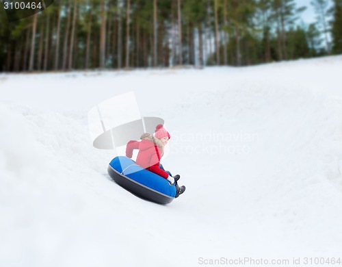 Image of happy teenage girl sliding down on snow tube