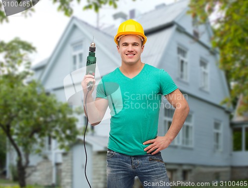 Image of happy male builder in helmet with electric drill