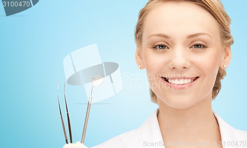 Image of happy young female dentist with tools