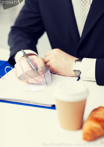 Image of businessman with coffee writing something