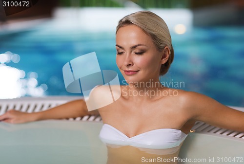 Image of happy womani sitting in jacuzzi at poolside