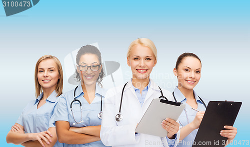 Image of smiling female doctor and nurses with tablet pc