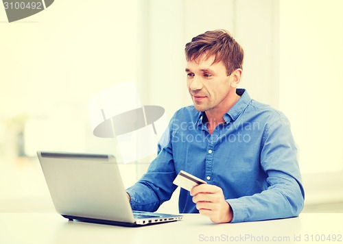 Image of man with laptop and credit card at home