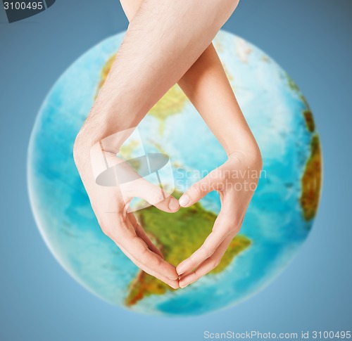 Image of human hands showing heart shape over earth globe