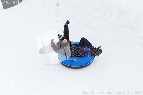 Image of happy young man sliding down on snow tube