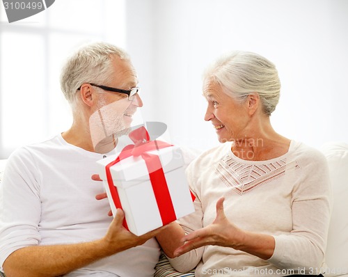 Image of happy senior couple with gift box at home