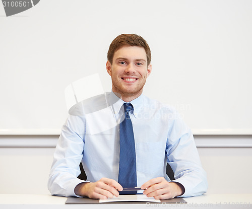 Image of smiling businessman sitting in office