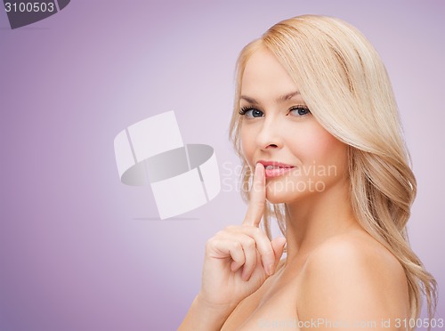 Image of beautiful young woman holding finger on her lips