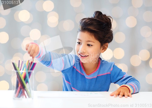 Image of happy little girl drawing with coloring pencils