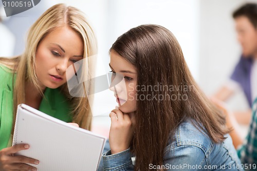 Image of student girls looking at notebook at school