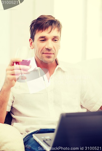 Image of man with laptop computer and glass of rose wine