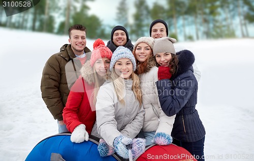 Image of smiling friends with snow tubes and selfie stick