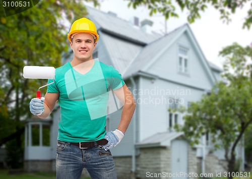 Image of smiling manual worker in helmet with pait roller