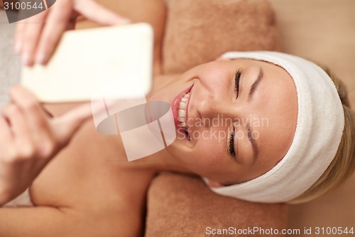 Image of close up of smiling woman with smartphone in spa
