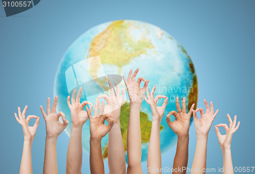 Image of human hands showing ok sign over earth globe