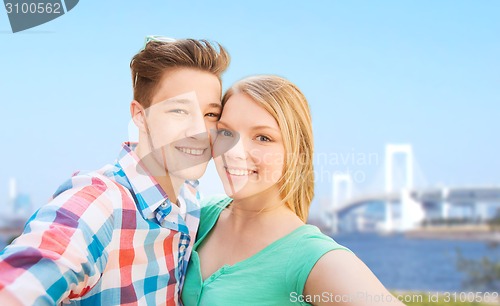 Image of smiling couple taking selfie over bridge