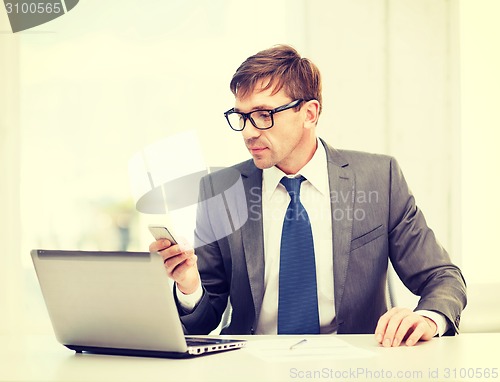 Image of businessman working with laptop and smartphone