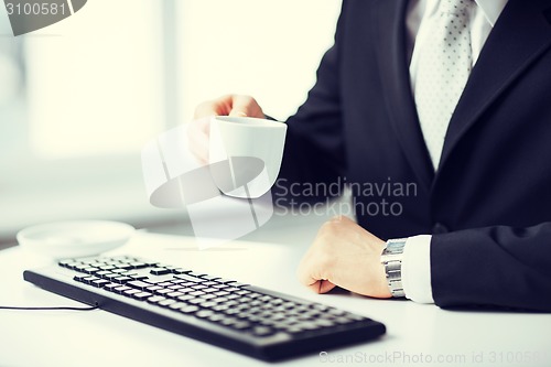 Image of man hands with keyboard drinking coffee