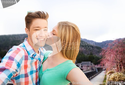 Image of couple kissing and taking selfie over asian town