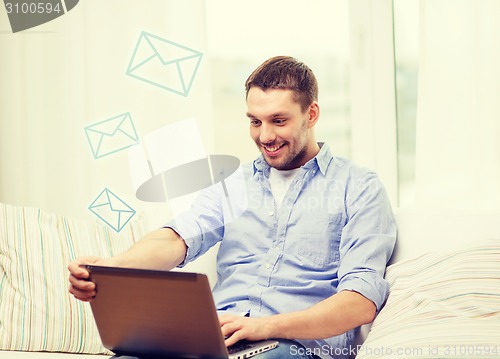 Image of smiling man working with laptop at home