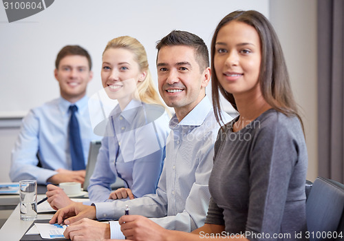 Image of group of smiling businesspeople meeting in office