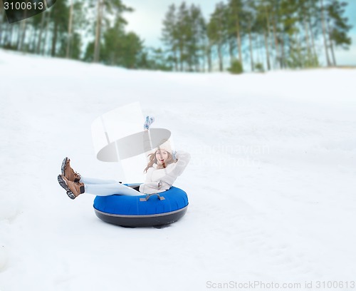 Image of happy teenage girl sliding down on snow tube