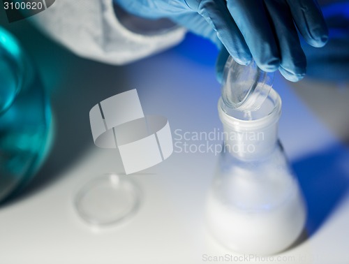 Image of close up of hand pouring chemical into flask