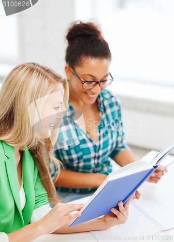 Image of smiling student girls reading book at school