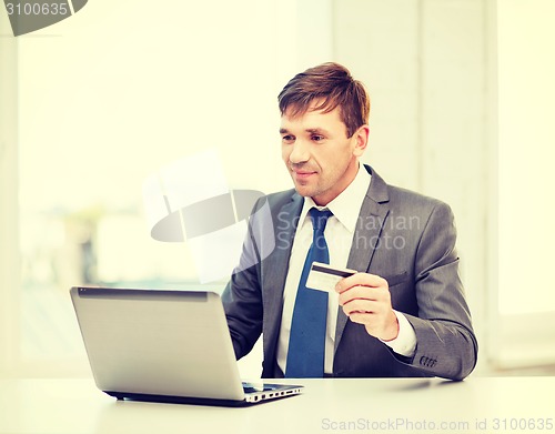 Image of man with laptop and credit card in office