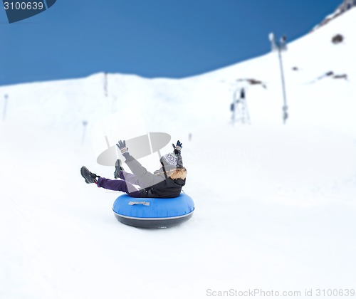 Image of happy young man sliding down on snow tube