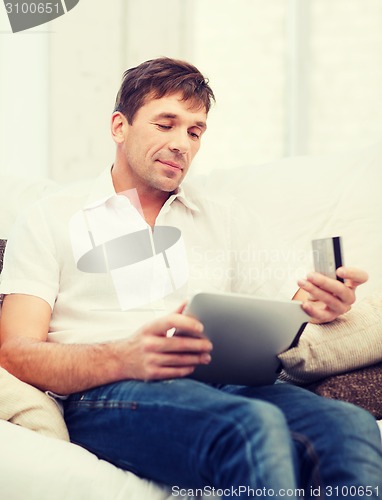 Image of man with tablet pc and credit card at home