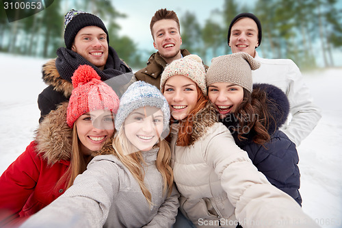 Image of group of smiling friends taking selfie outdoors