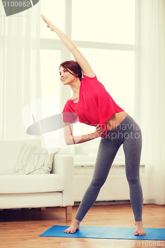 Image of smiling teenage girl streching at home