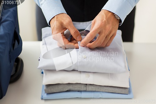 Image of businessman packing clothes into travel bag