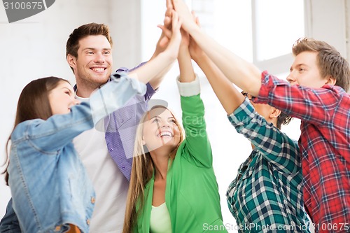 Image of happy students giving high five at school