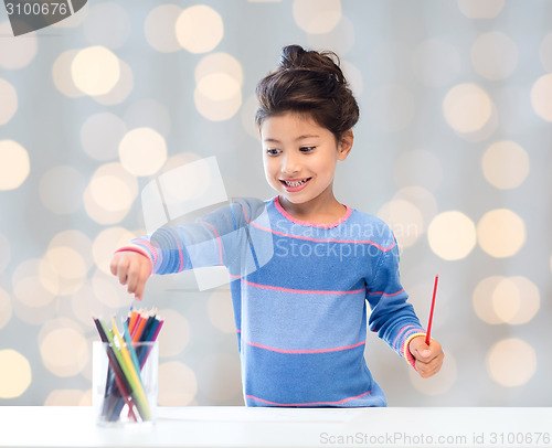 Image of happy little girl drawing with coloring pencils