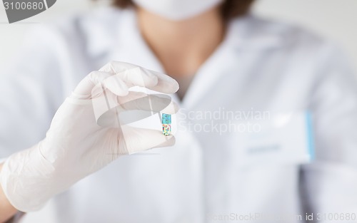 Image of close up of scientist holding pill in lab